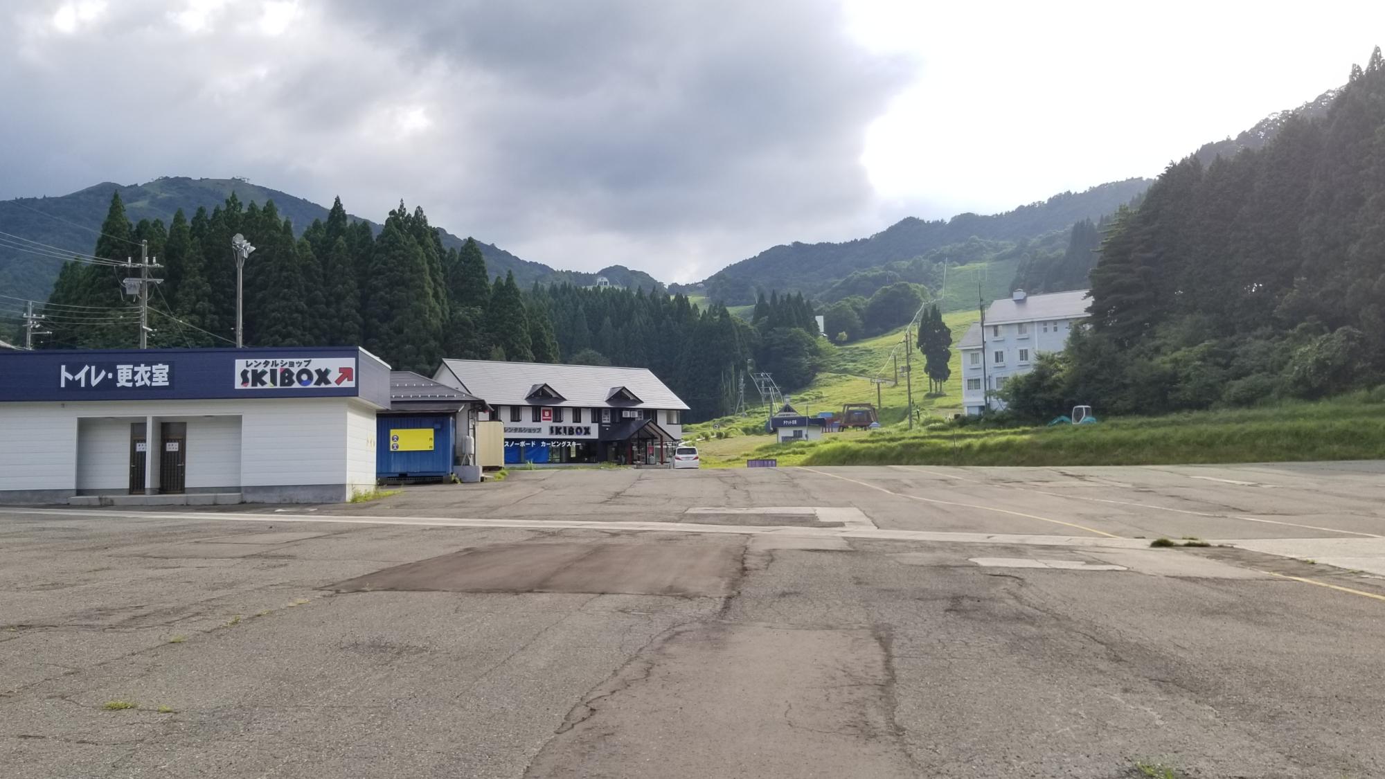 アスファルトの広場に建物が数件建っている写真