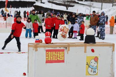 イベント会場で、雪球を的に当てて得点を競うゲームをしているこどもの写真