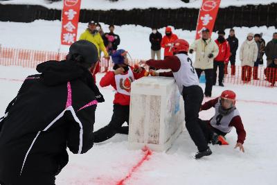 シェルターを挟み雪球を投げ合う選手達の写真