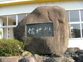 施設の敷地内に設置された校名が刻まれた記念碑の様子の写真