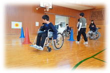 体育館に三角コーンが置かれ、間を車いすが通っている写真