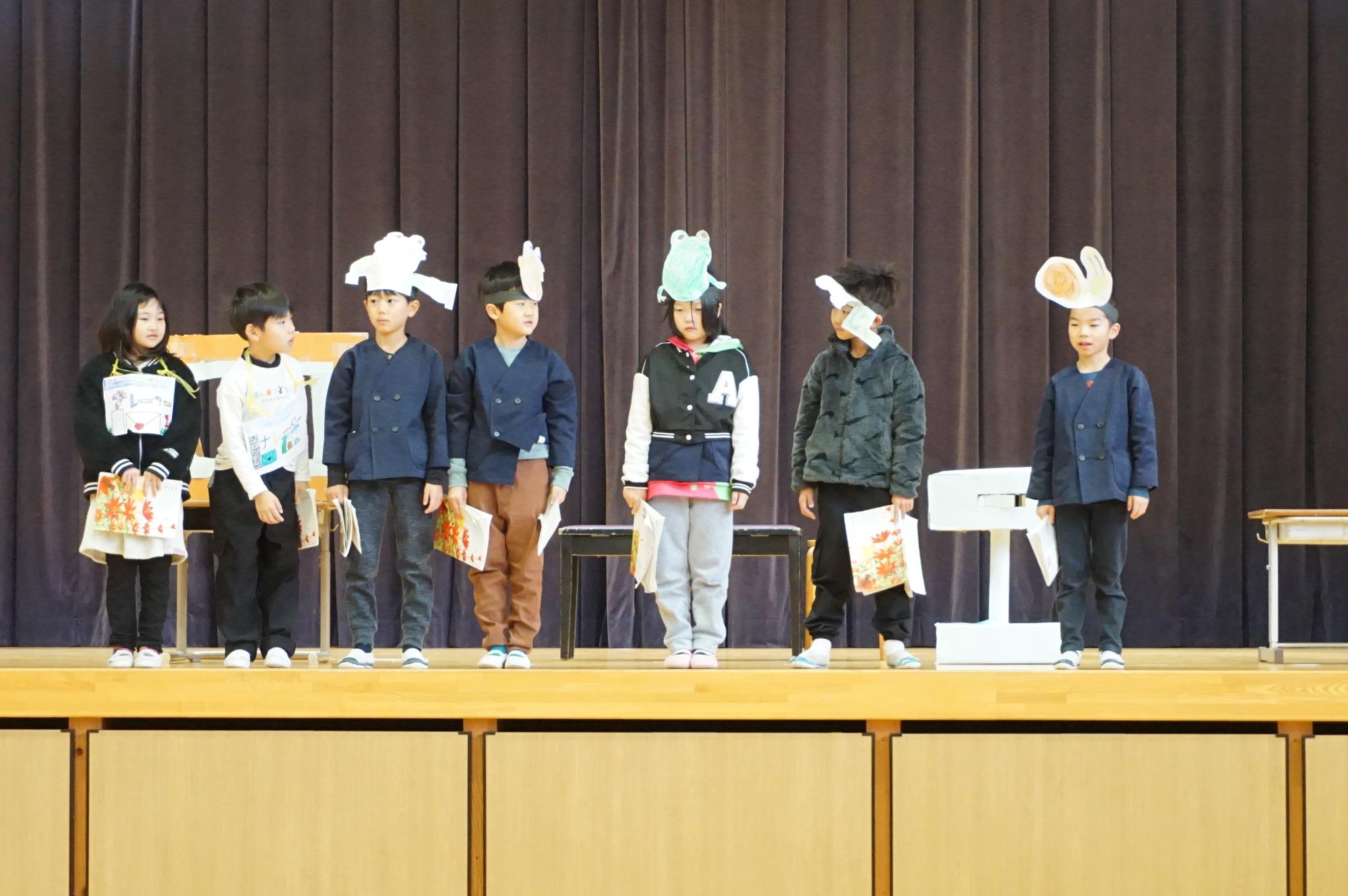 舞台上でお面を頭に付けた児童たちが出し物をしている様子の写真
