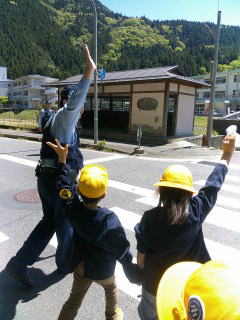 横断歩道で手を挙げて歩く子どもたちの写真