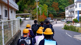 小学生と中学生が住宅街を歩いている様子を後ろから撮影した写真
