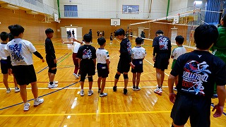 ネットが張られた体育館で整列している児童たちの写真