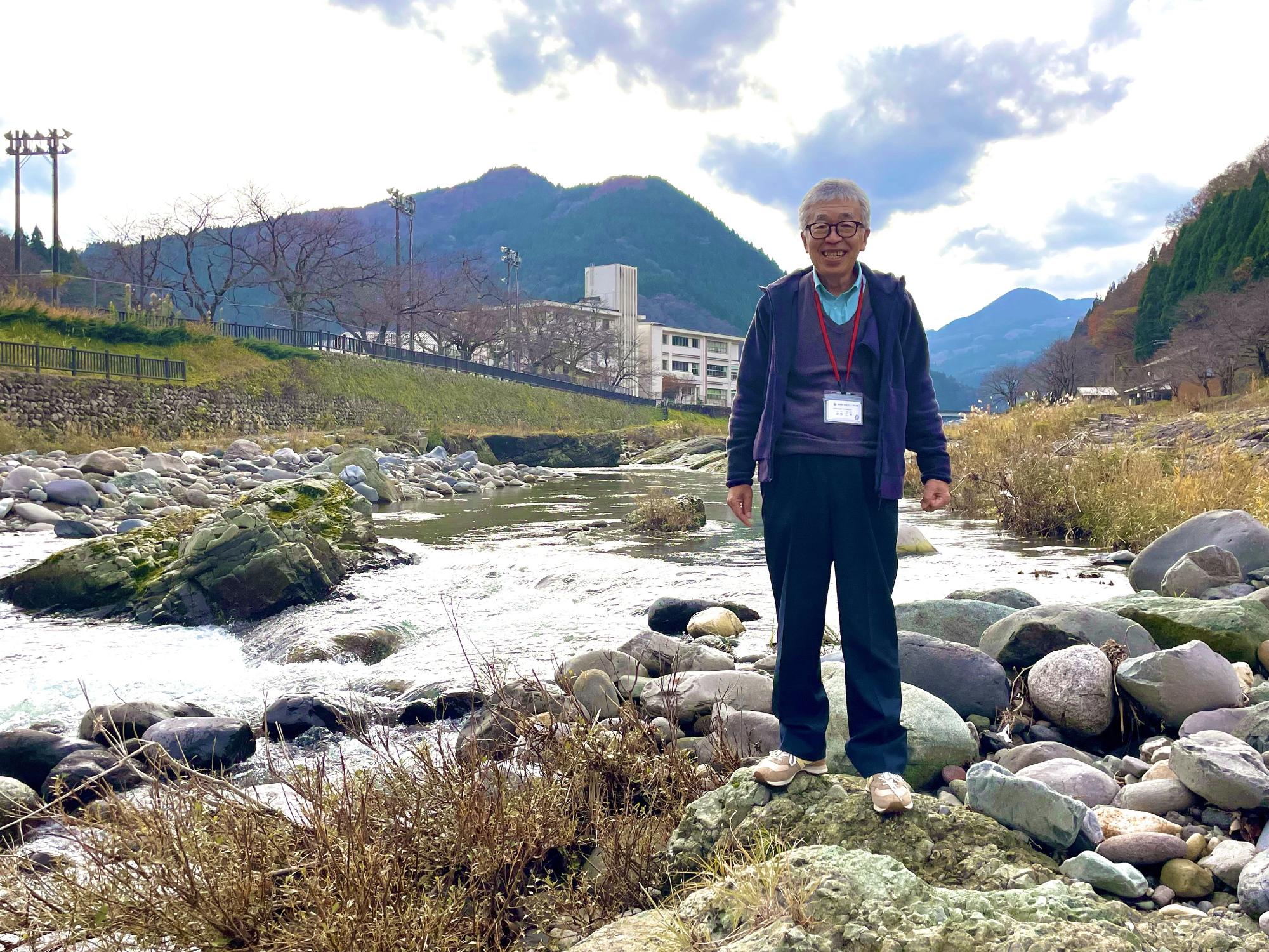 川の近くの大きな石の上に立っている衣笠 仁博さんの写真