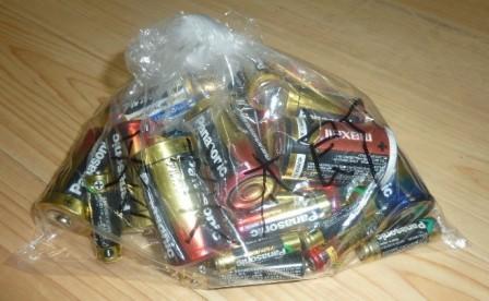 文字が書かれている透明な袋に入っている沢山の乾電池の写真