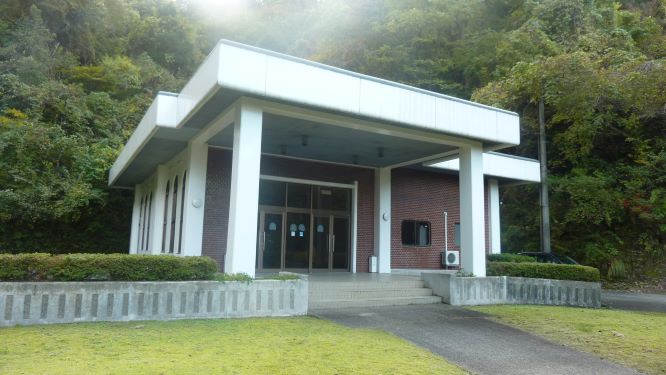 緑に囲まれた中に白い柱のエントランスがある建物の写真