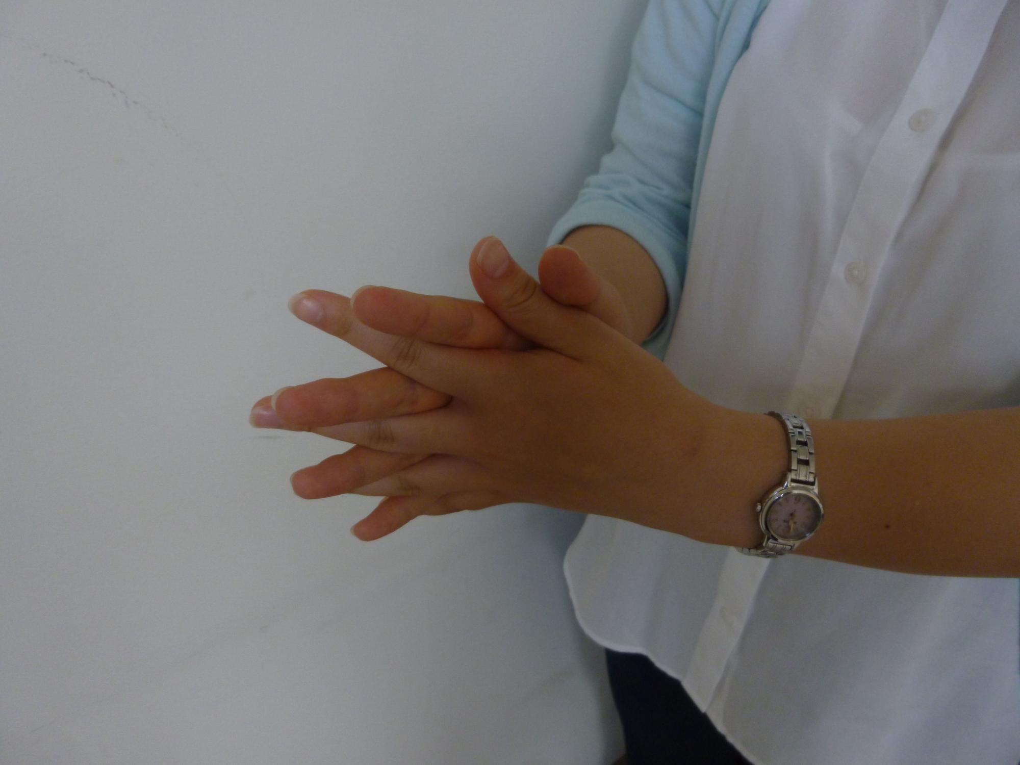 両手を指を絡めながら互いにこすり合わせている写真