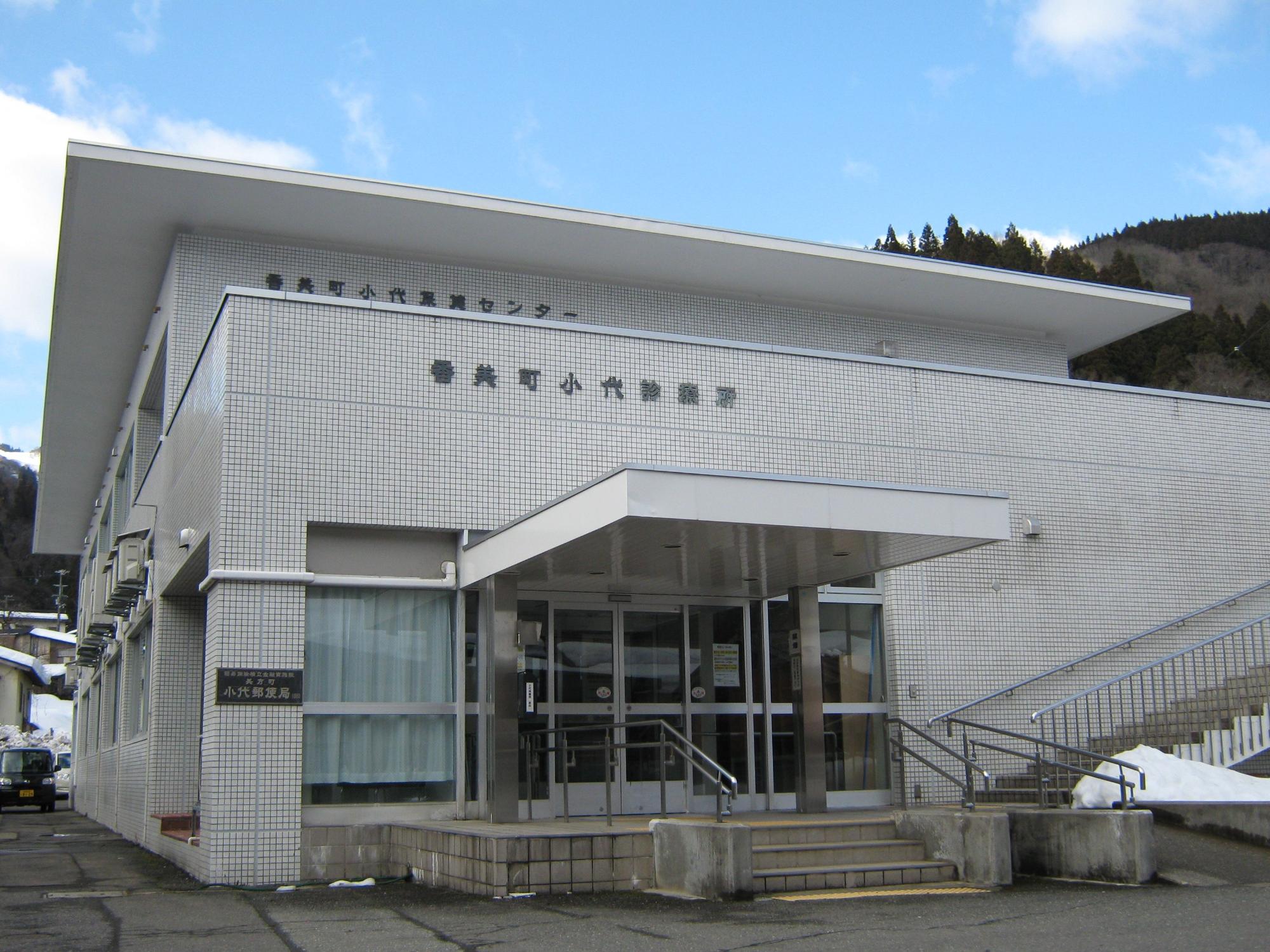 入口に庇と自動ドアがある白い建物の外観の写真