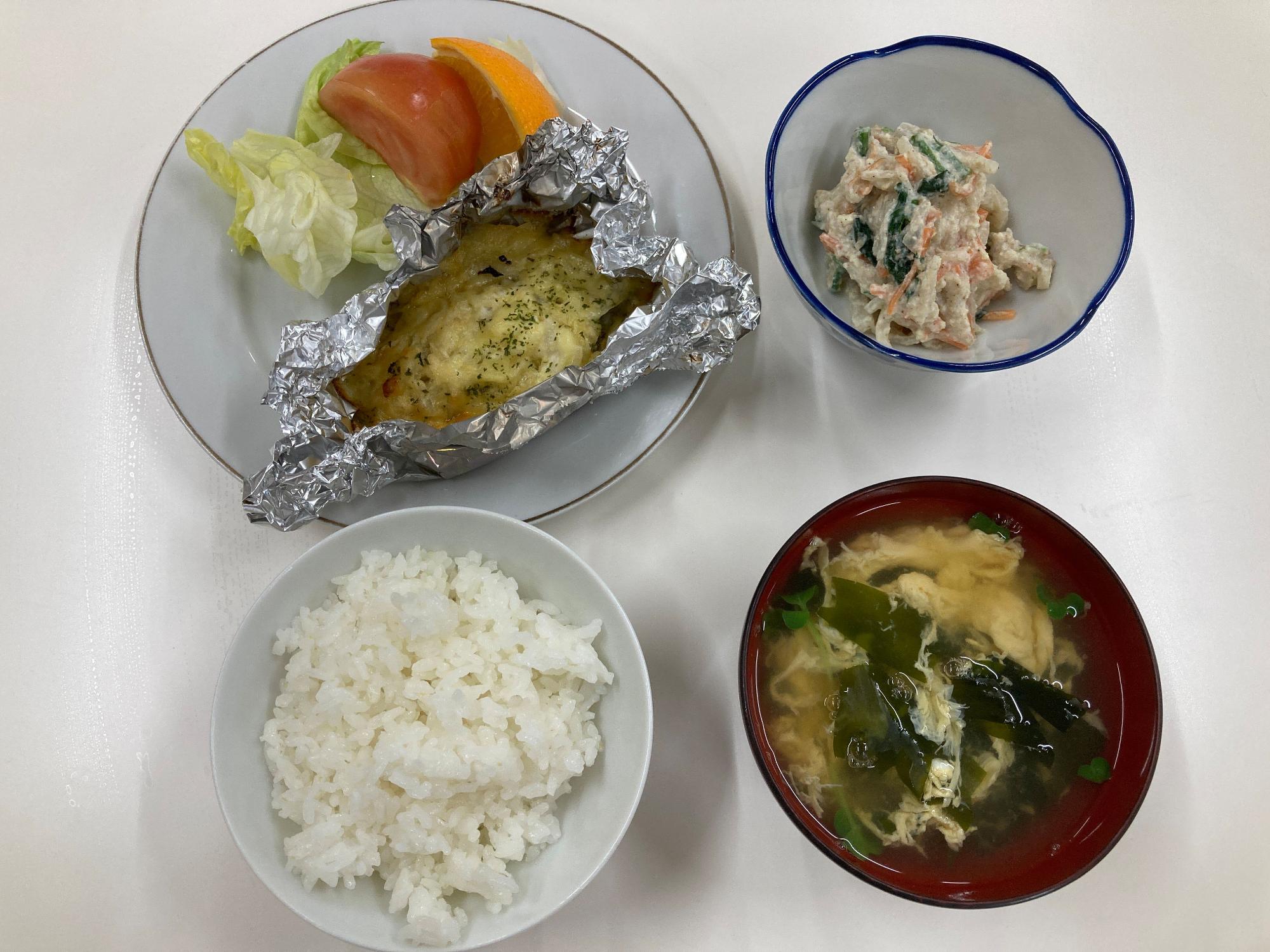 ごはんとみそ汁にホイル焼きと和え物がテーブルに置かれた一食の写真