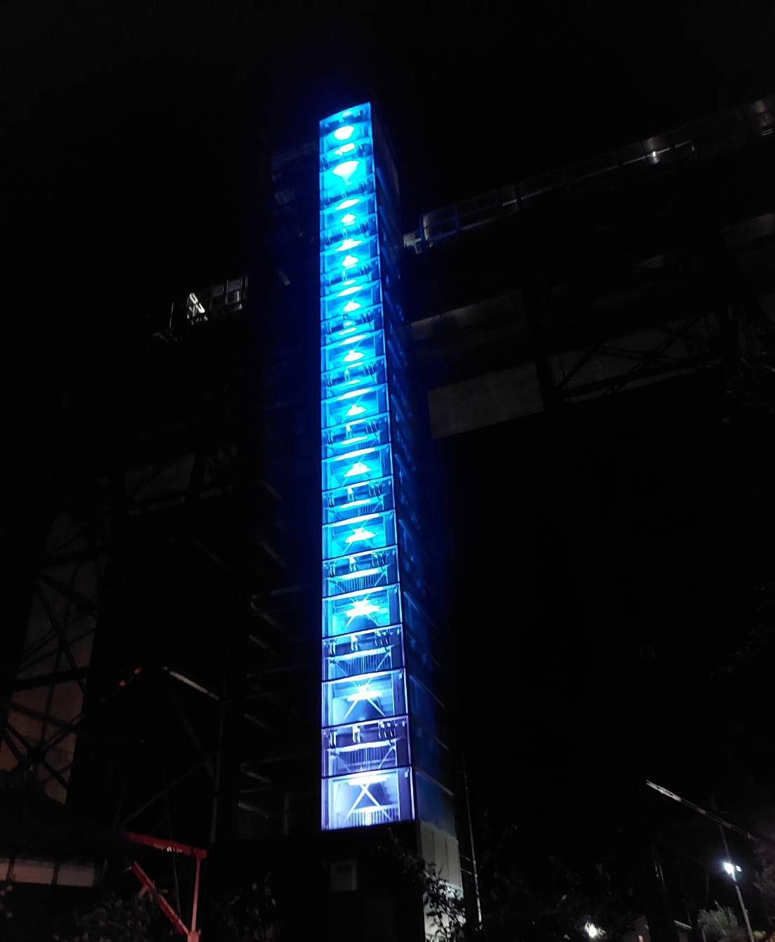 周囲が暗い中で青色にライトアップされたとても高い建物の写真